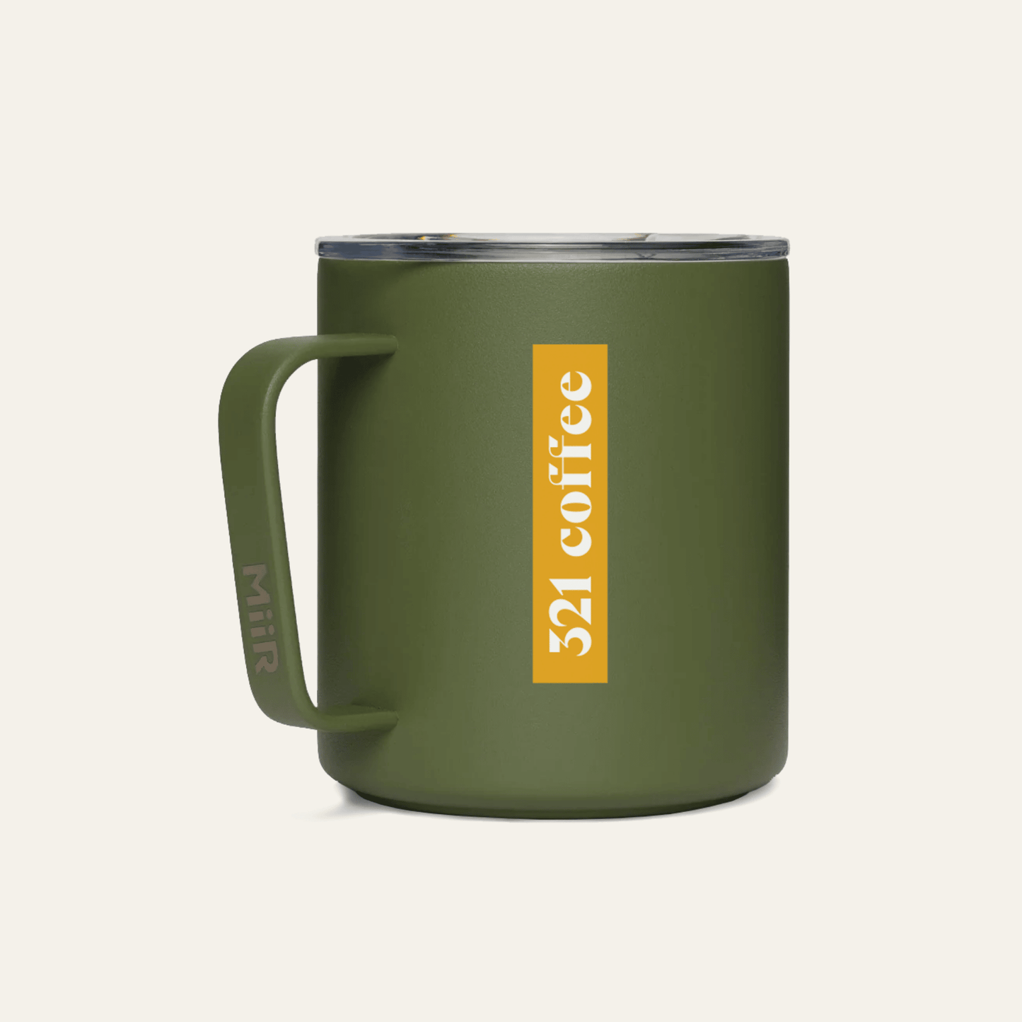 The back of a dark green metal camp mug with "321 Coffee" printed in white on a yellow background on the mug.