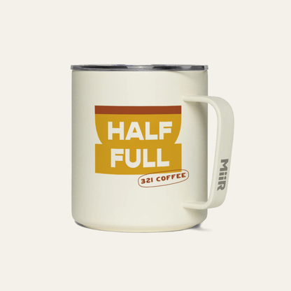 A light beige metal camp mug with "Half Full" printed in white on a yellow coffee mug.